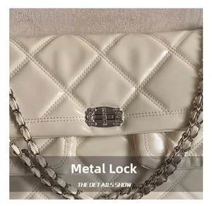 Close-up of cream quilted crossbody bag with rhinestone hardware lock and chain strap