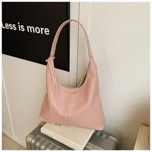 Sac fourre-tout rose à texture litchi sur une valise argentée pour un look de voyage