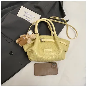 Détail du sac seau tressé jaune clair avec bandoulière et charmant ours en peluche