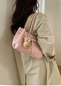 Detail of soft leather tote bag with decorative buckle and plush bear charm on model