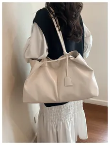 Close-up of a large beige tote bag in glossy synthetic leather with elegant shoulder strap