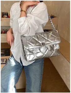 Close-up of a silver metallic quilted handbag with chain strap and twist-lock on a model