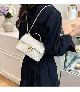 Détail du sac matelassé blanc avec bandoulière en chaîne dorée et fermoir pivotant