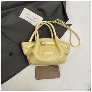 Détail d'un sac seau tissé jaune clair avec écusson logo et poignées supérieures élégantes