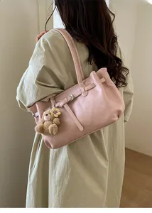 Pink faux leather tote bag with brown plush bear charm and metallic buckle details