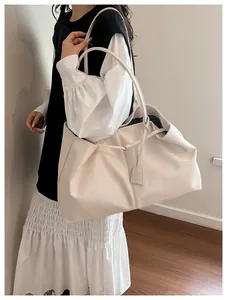 Detail view of large cream tote bag with long shoulder straps and square tag charm