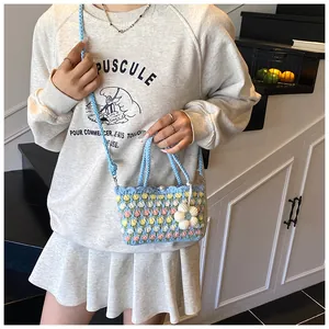 Detail of hand-crocheted blue bucket bag with pink tulip patterns and floral charm