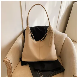 Détail du sac bandoulière beige en cuir grainé avec étiquette de marque élégante