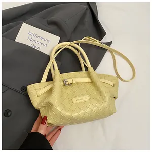Gros plan du sac seau tressé présentant la texture du cuir et le logo métallique