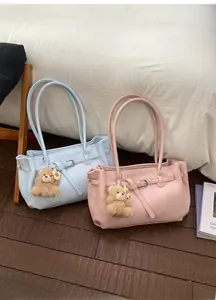 Detail of soft leather tote bags in pink and blue colors with plush bear charms