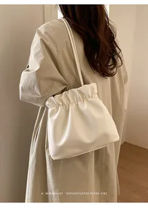 Minimalist cream bucket bag featuring soft PU leather texture on female model shoulder