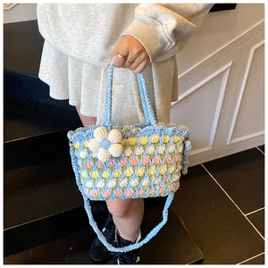 Detail of hand-woven tulip bucket bag featuring a 3D white floral charm and woven strap