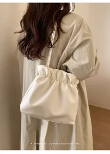 Detail of white pleated bucket bag showing supple leather texture and thin shoulder strap