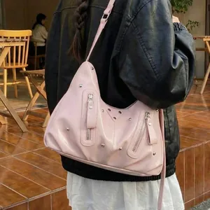 Rosafarbene Schultertasche mit Nieten im Y2K-Stil, getragen von einem Modell im Freien