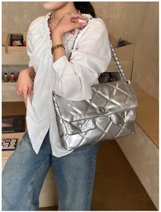 Close-up of silver quilted chain shoulder bag with dual front pockets and metal lock