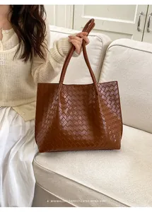 Détail de la texture en cuir tressé marron et des poignées de ce grand sac cabas