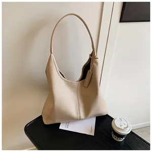 Détail du sac hobo beige en cuir grainé avec bandoulière et étiquette assortie