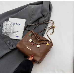 Détail du sac seau matelassé marron avec breloque cœur dorée et bandoulière en chaîne