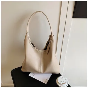 Gros plan d'un sac cabas beige grainé avec couture verticale et étiquette en cuir