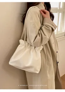 Detailed side view of off-white drawstring bucket bag on model in minimal setting