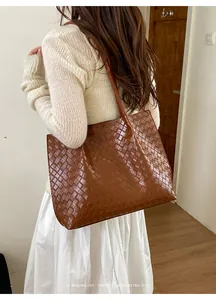 Détail de la texture en cuir tressé et des fines bandoulières du grand sac cabas marron
