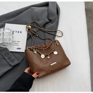 Vue détaillée du sac seau matelassé marron avec pendentifs cœur colorés sur un blazer