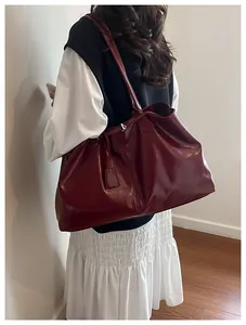 Detail of burgundy large tote bag with leather texture and shoulder straps