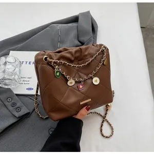 Sac seau matelassé marron avec breloques en émail coloré et détails de chaîne dorée