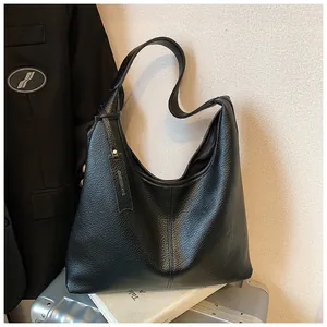 Gros plan sur la texture en cuir grainé noir et l'étiquette de ce grand sac cabas