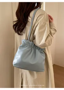 Side view of a light blue minimalist bucket bag with pleated leather texture and slim straps