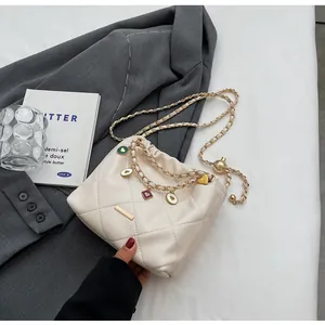 Détail du sac seau matelassé crème avec chaîne dorée et breloques de cœur colorées