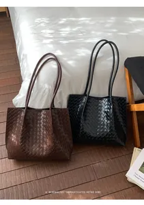 Détail de la texture en cuir tressé sur de grands sacs cabas en marron et noir