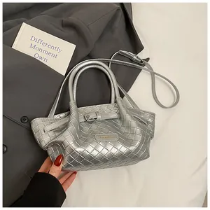 Détail du sac seau argenté à texture tressée avec logo en métal et bandoulière