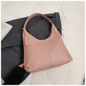 Détail du sac cabas en cuir grainé rose avec coutures verticales sur literie blanche