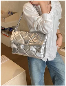 Silver quilted crossbody bag with metal chain strap shown in a modern lifestyle setting