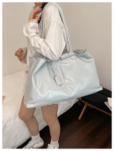 Detail of light blue glossy tote bag with twin shoulder straps and shiny texture