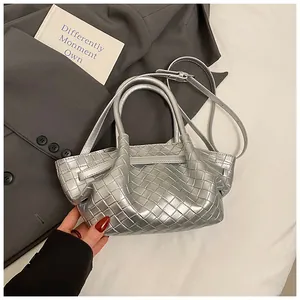 Détail d'un sac seau tressé argenté avec texture métallique sur blazer gris et lin