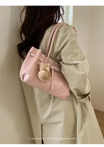 Pink faux leather tote bag with long handles and a cute plush bear charm on a model
