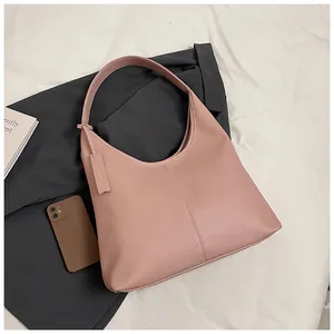 Détail d'un sac hobo rose en cuir grainé avec une étiquette latérale assortie