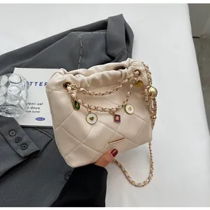 Détail du sac seau en cuir matelassé avec chaîne dorée et breloques en émail coloré