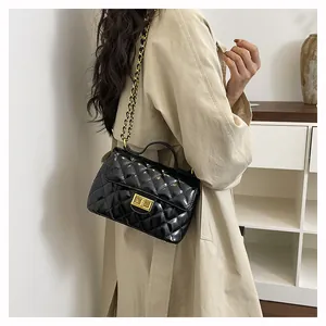Détail du sac matelassé en cuir verni noir avec fermoir doré sur un trench-coat élégant