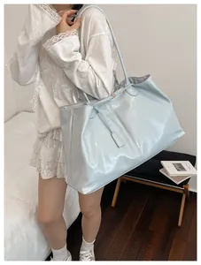 Detail shot of light blue glossy patent leather tote bag with thin double shoulder straps