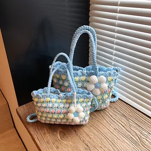 Handmade crochet woven bag with floral patterns and pearl closure on wooden windowsill