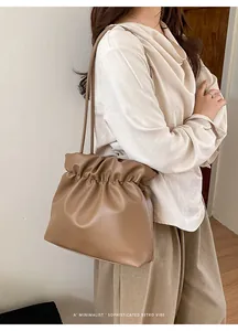 Close-up of brown textured leather bucket bag with elegant pleated drawstring detail