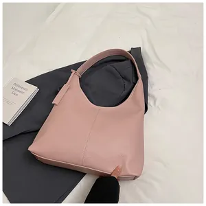 Gros plan détaillé de la texture en cuir rose sur un sac à bandoulière demi-lune épuré