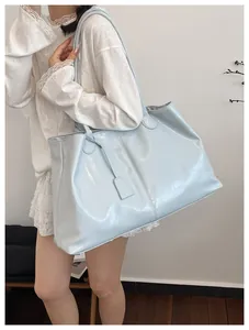 Detail of light blue high-gloss tote bag showing smooth patent leather texture and minimalist charm