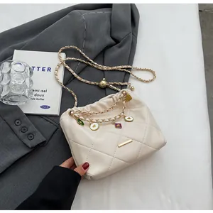 Détail du sac matelassé blanc cassé avec chaîne dorée et breloques colorées