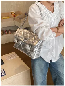 Detail view of silver quilted chain bag featuring metallic finish and rhinestone logo
