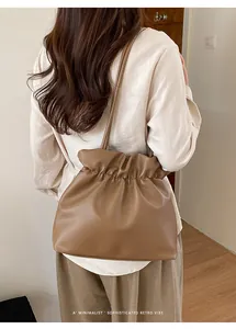 Rear view of a model wearing a brown pleated leather bucket bag in a retro minimalist style