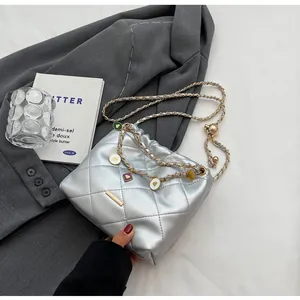 Sac seau matelassé argenté avec chaîne dorée et breloques en forme de cœur